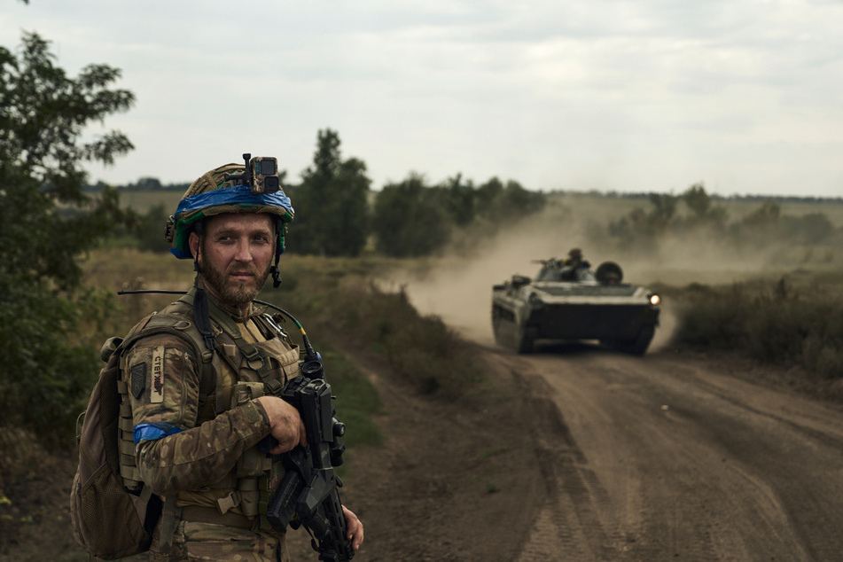 Ein Soldat der 3. Separatistenbrigade der Ukraine blickt auf vorbeifahrende Schützenpanzer.