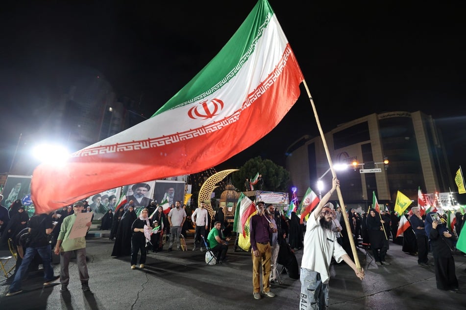 A demonstrator waves a large Iranian flag in Tehran on June 7, 2026.