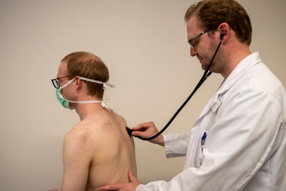 Der Internist Dominik Buckert (r.) hört in der Corona-Ambulanz des Universitätsklinikums mit einem Stethoskop die Lunge eines Patienten ab. Ein Forschungsprojekt der Uniklinik Ulm beschäftigt sich seit Anfang des Jahres mit den Langzeitfolgen einer Covid-19-Erkrankung für Herz und Lunge.