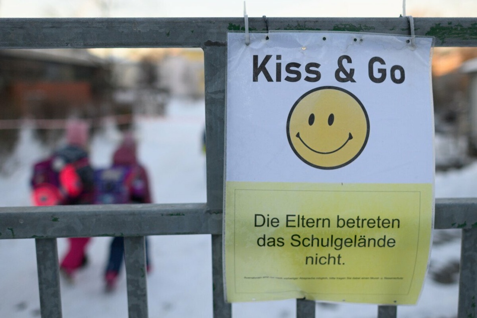 Ein Schild mit einem Smiley und der Aufschrift "Die Eltern betreten das Schulgelände nicht" hängt am Tor der Regenbogenschule in Dresden.