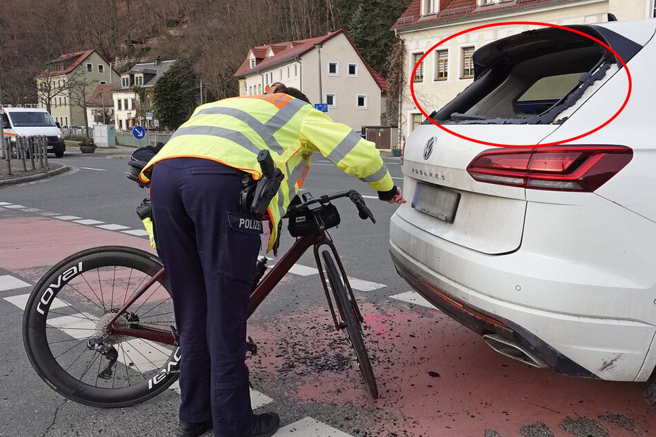 Eine Polizistin untersucht das Unfallrad und den VW Touareg nach Spuren. Die Heckscheibe des Touareg ist komplett zerstört.