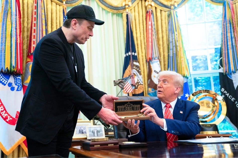 President Donald Trump (r.) presents a "key to the White House" to Elon Musk during a news conference in the Oval Office of the White House in Washington, DC, on May 30, 2025.