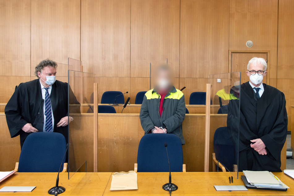 Alexander M. steht in Handschellen hinter der Anklagebank zwischen seinen Anwälten Marcus Steffel (l.) und Ulrich Baumann.