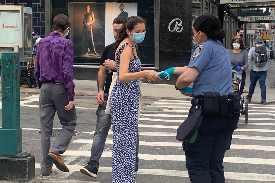 Eine Polizistin verteilt Schutzmasken zur Eindämmung des neuartigen Coronavirus an Passanten auf der Straße in Manhattan.