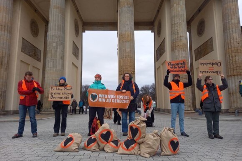 Aktivisten der "Letzten Generation" stehen am Samstagnachmittag vor dem Brandenburger Tor mit Sandsäcken.
