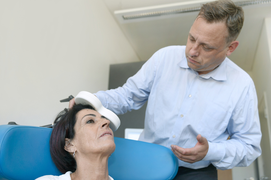 Christian Plewnia, Facharzt für Psychiatrie und Psychotherapie an der Universitätsklinik Tübingen legt der Patientin Erika Fuchs eine Magnetspule an.