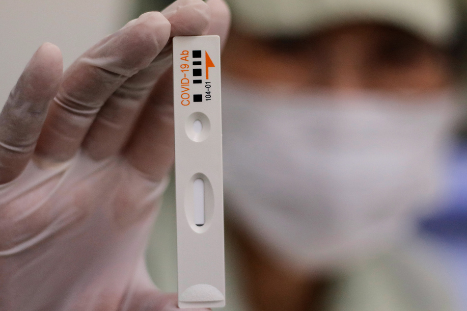 Ein Mitarbeiter von Boditech Med in Chunchon, Südkorea, hält ein Teströhrchen für einen Covid-19-Antikörpertest in der Hand.