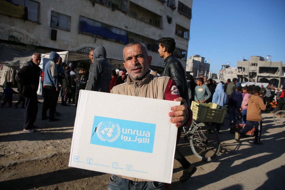 A Palestinian man carries an aid box provided by UNRWA in Khan Younis in the southern Gaza Strip on January 21, 2025.