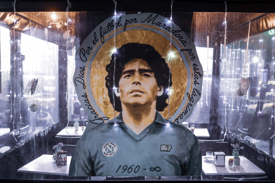 Ein Porträt von Diego Armando Maradona hängt vor einem Restaurant in Neapel (Italien).