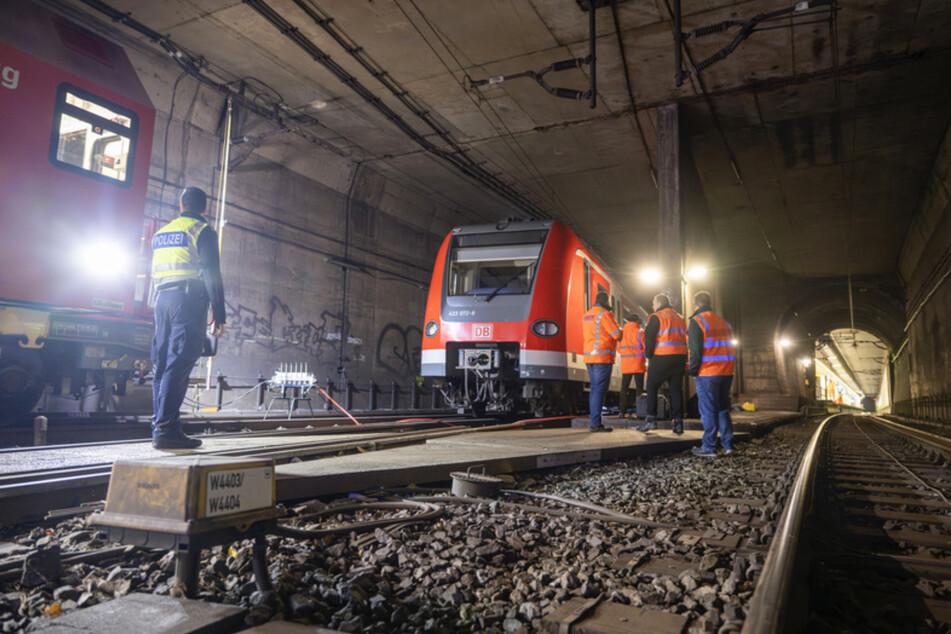 Bundespolizisten und Bahnarbeiter stehen in den Morgenstunden an der entgleisten S-Bahn im Tunnel.