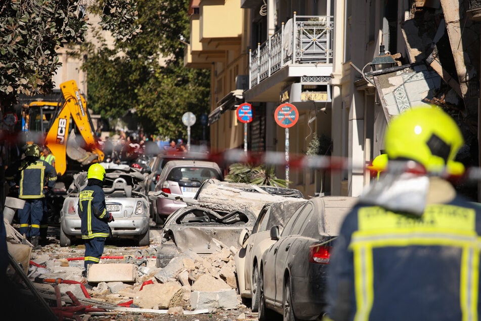 Feuerwehrleute arbeiten zwischen Trümmern und schwer beschädigten Autos am Ort der Explosion in der Athener Altstadt.