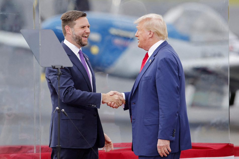 Donald Trump shakes hands with his running mate, JD Vance, in a bulletproof glass house at their rally in Asheboro, North Carolina.