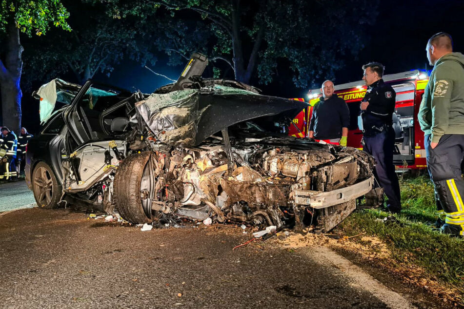 Einsatzkräfte stehen vor dem Unfallwagen.