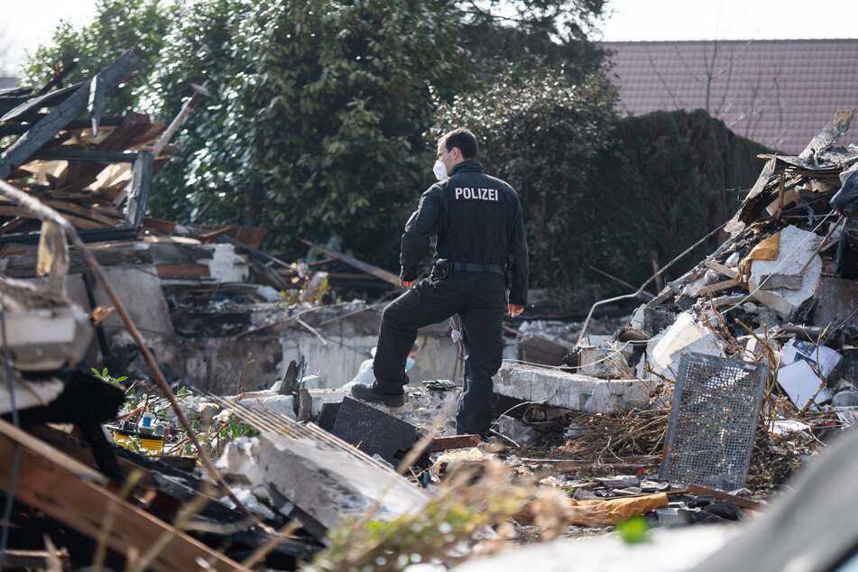 Einsatzkräfte arbeiten in den Überresten des Wohnhauses.