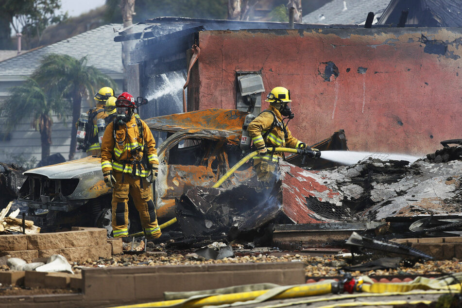 Firefighters put out hot spots at the scene of the fatal plane crash on Monday.