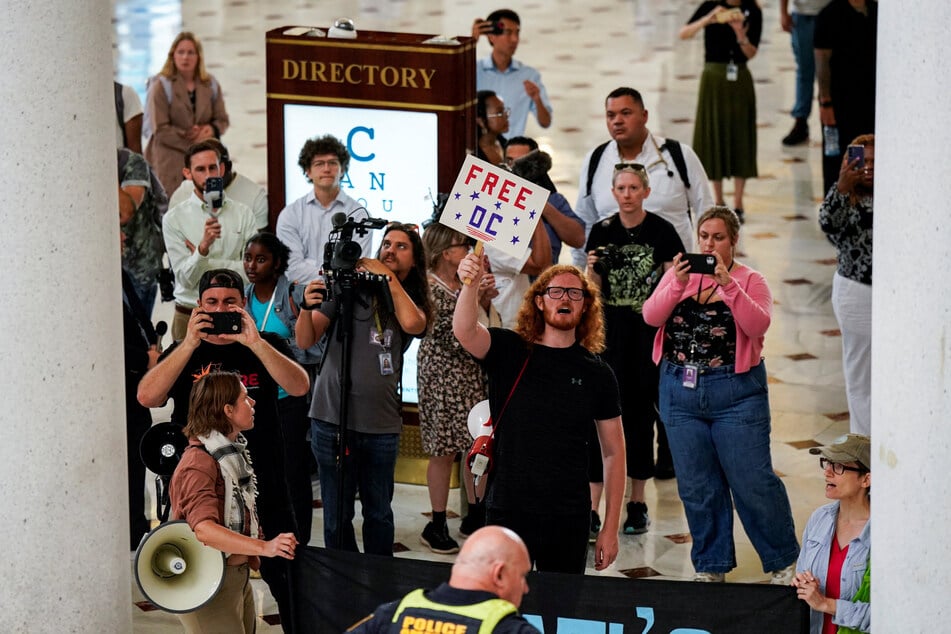 Demonstrators chant as Vice President JD Vance, Defense Secretary Pete Hegseth, and White House Deputy Chief of Staff Stephen Miller visit members of the National Guard, at Union Station in Washington DC on August 20, 2025.