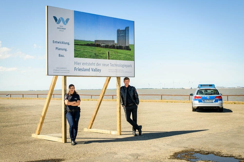 "Friesland - Haifischbecken": Süher Özlügül (Sophie Dal, l.) und Henk Cassens (Maxim Mehmet, r.) lehnen an einer Plakatwand. Ein "Silicon Valley" soll in Leer entstehen...