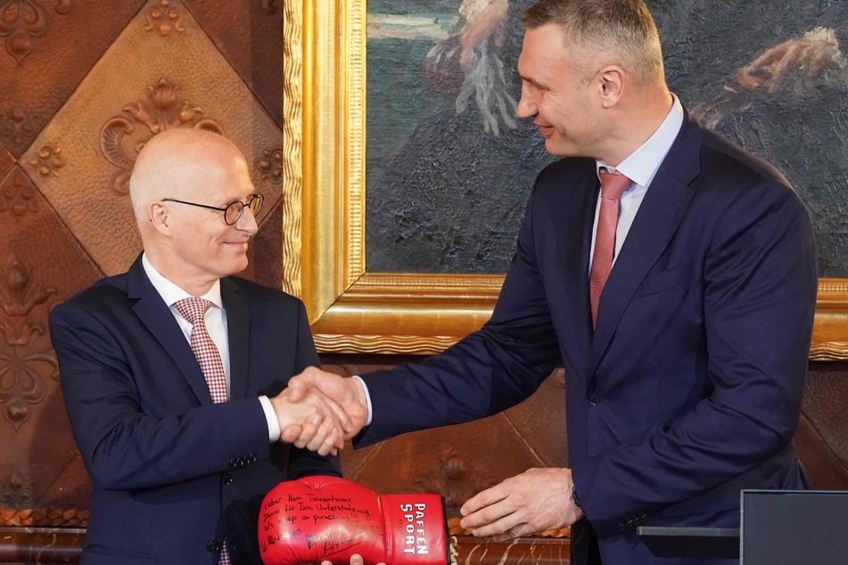 Vitali Klitschko überreicht Bürgermeister Tschentscher einen Boxhandschuh mit Widmung.