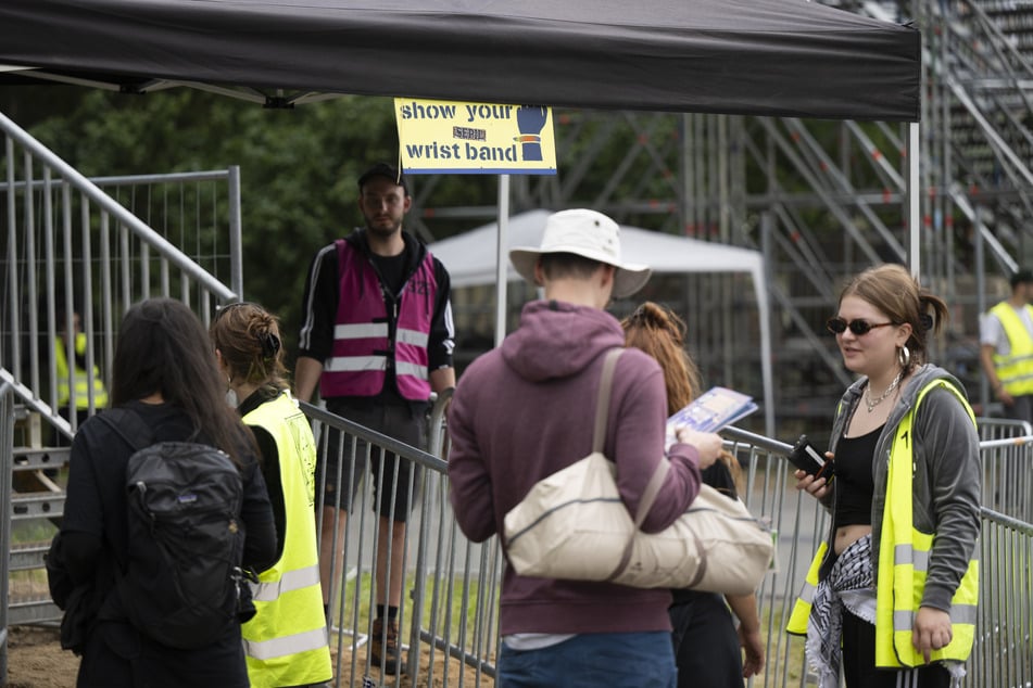 Besucher stehen bei der Einlasskontrolle am Eingang des Festivalgeländes.