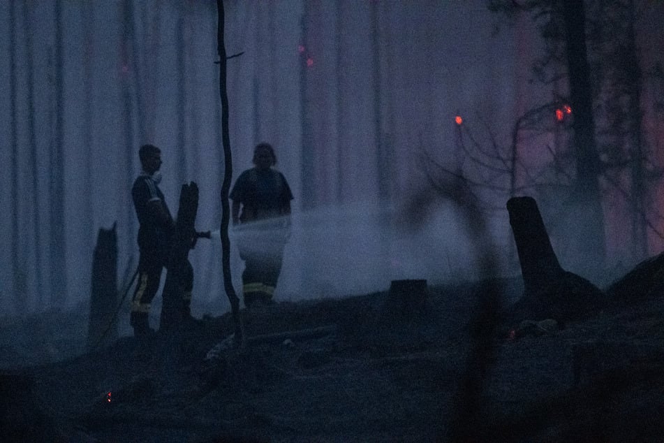 Thüringen, Reichmannsdorf: Einsatzkräfte der Feuerwehr löschen in einem Wald Glutnester.