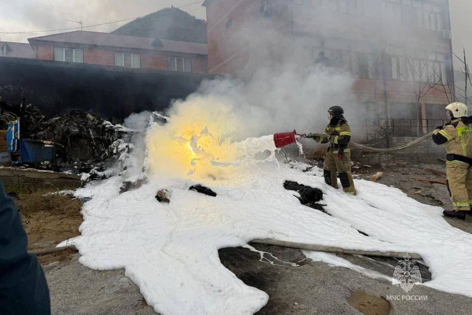 Después del accidente, los bomberos eliminan los restos con abundante espuma.