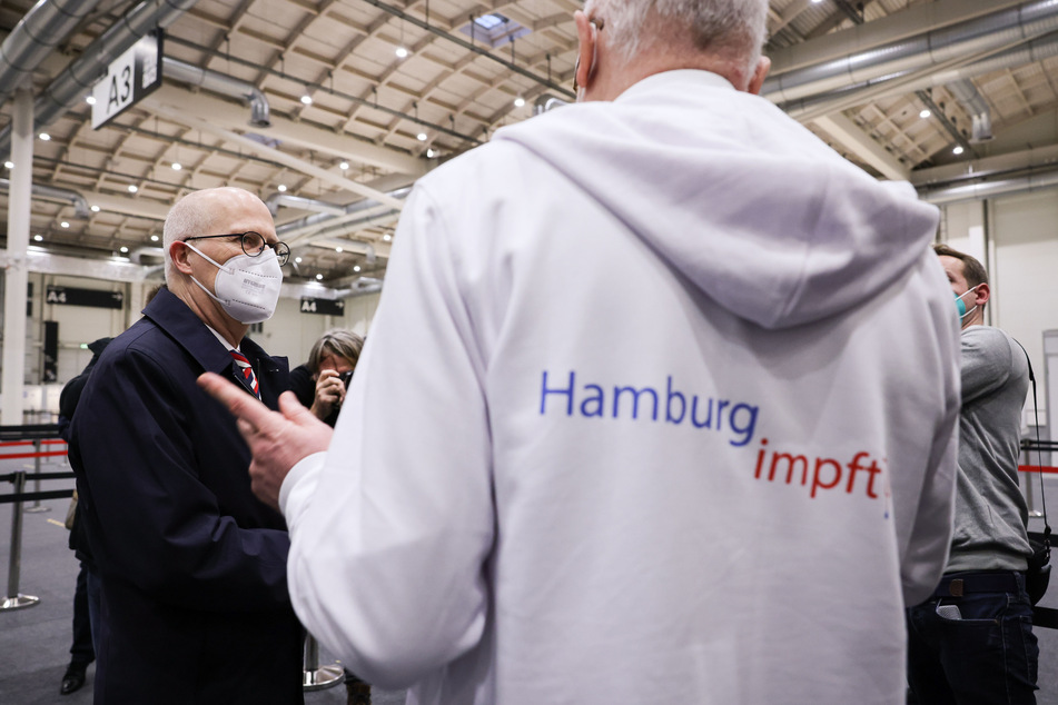Peter Tschentscher (SPD, l) und Dirk Heinrich, ärztlicher Leiter des Impfzentrum Hamburg, unterhalten sich bei einem Medientermin im Impfzentrum in den Messehallen.