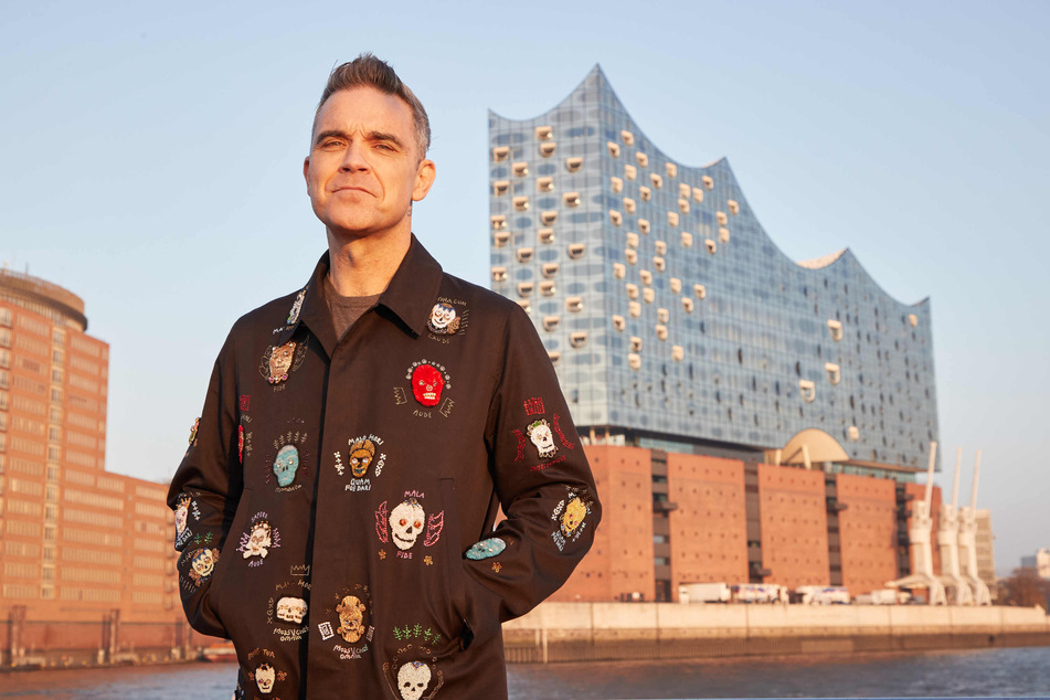 Robbie Williams (48) posiert vor seinem Konzert in der Elbphilharmonie für die Fotografen. Das spektakuläre Konzerthaus ist im Hintergrund zu sehen.