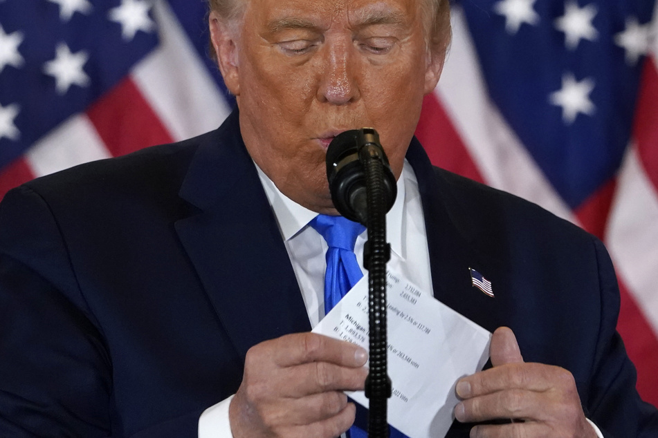 Donald Trump, Präsident der USA, nimmt einen Zettel aus seiner Jacke während er im Ostsaal des Weißen Hauses spricht.