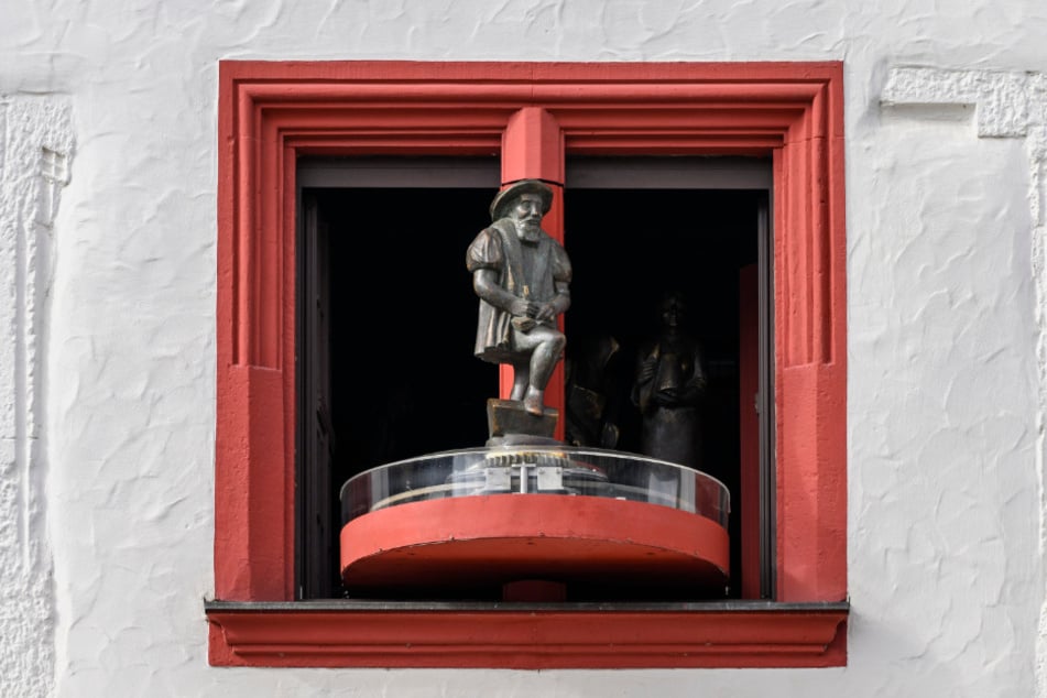 Sechs Figuren, hier der Kaufmann, drehen sich zur Musik.