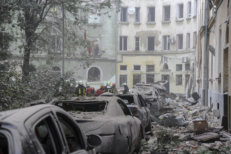 Rettungskräfte versammeln sich vor beschädigten Gebäuden in Lwiw, während die Suche nach Opfern nach einem Raketenangriff weitergeht.