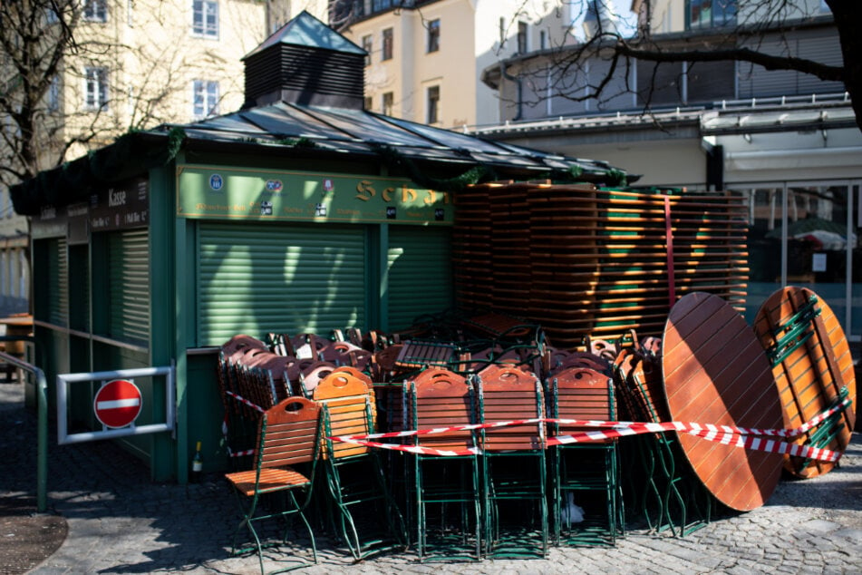 Zusammengeklappte Stühle und Tische von einem Biergarten sind auf dem fast menschenleeren Viktualienmarkt zu sehen.