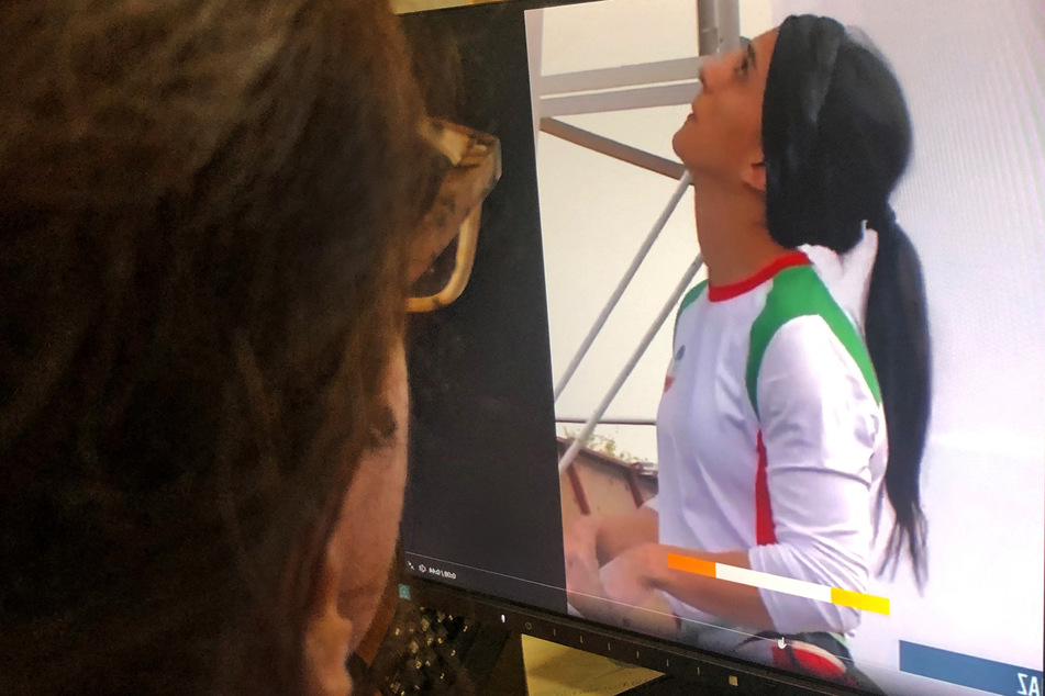 A woman watches footage of Iranian climber Elnaz Rekabi competing without a hijab on Tuesday.