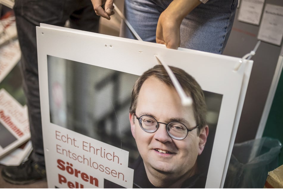 Ehrenamtliche Unterstützer ziehen Kabelbinder durch die Plakate. Diese Vorbereitung erleichtert das Aufhängen vor Ort.