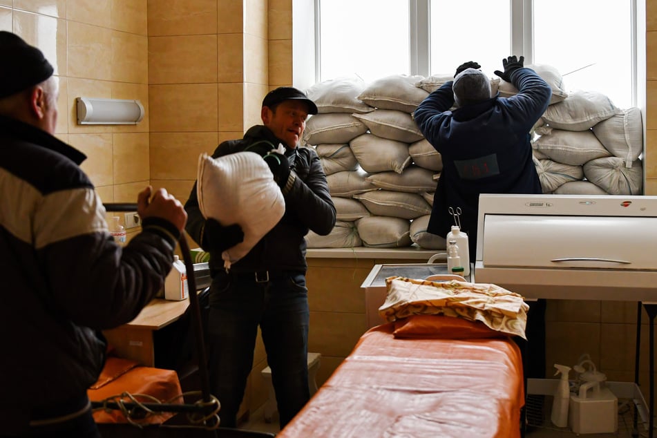 Arbeiter platzieren Sandsäcke vor dem Fenster zum Schutz vor Angriffen im Krankenhaus der Stadt Kramatorsk.