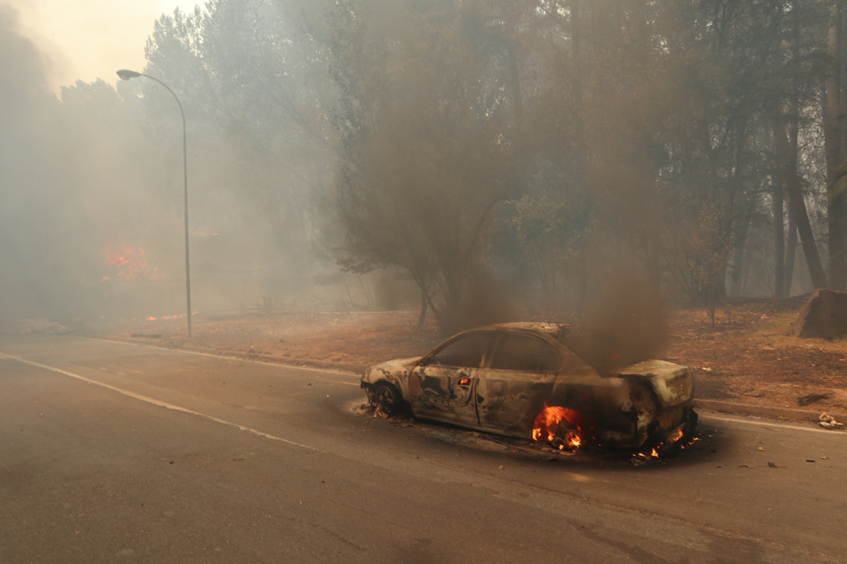 Ein Wagen brennt inmitten des Waldbrandes lichterloh.