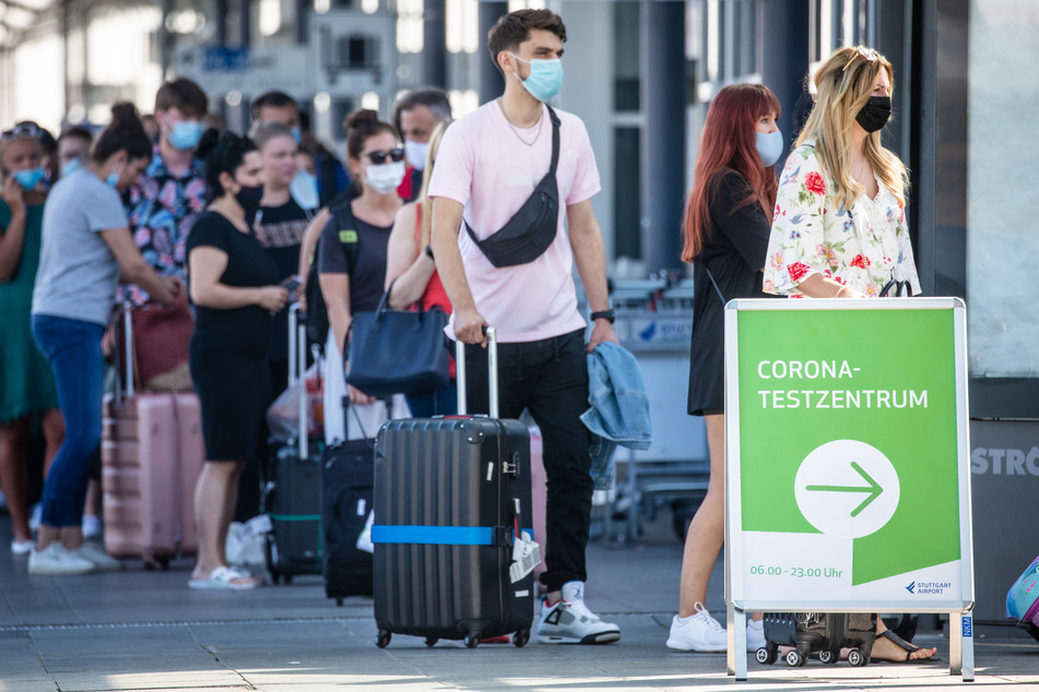 Reiserückkehrer, vorwiegend aus Spanien, stehen mit Mundschutz vor dem Corona-Testzentrum am Flughafen Stuttgart. (Symbolbild)