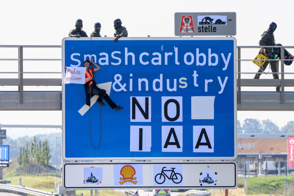 Ein Aktivist hängt an einer Schilderbrücke über der Autobahn A9 bei Fürholzen in Fahrtrichtung München und hält ein Banner mit der Aufschrift "Autos zerstören" in den Händen, während Polizisten eines Spezialeinsatzkommandos sich auf der Schilderbrücke in Position bringen.