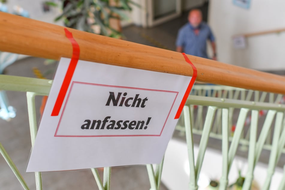 Ein Zettel mit der Aufschrift "Nicht anfassen!" hängt an einem Geländer einer Grundschule in Eisenhüttenstadt.