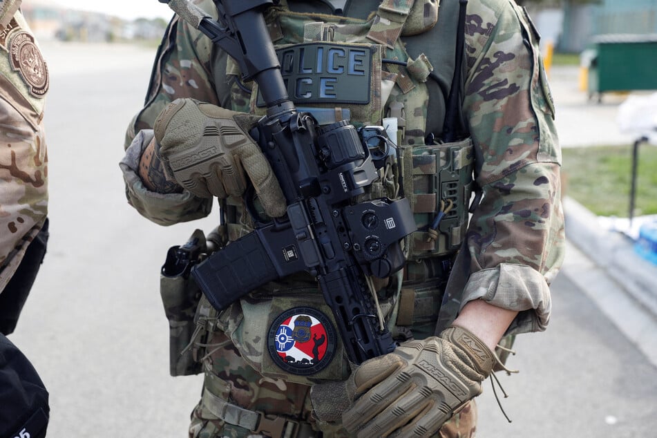 An ICE officer holds a weapon during a protest outside a detention facility in Broadview, Illinois, on September 12, 2025.