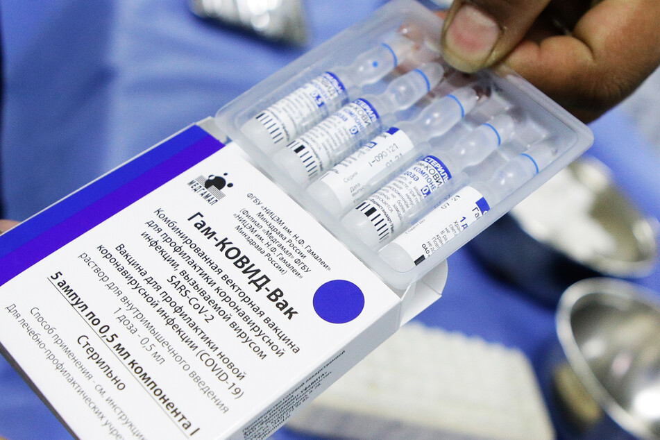 Ein Mitarbeiter des Gesundheitswesens macht eine Verpackung mit mehreren Dosen des Corona-Impfstoffs Sputnik V auf.