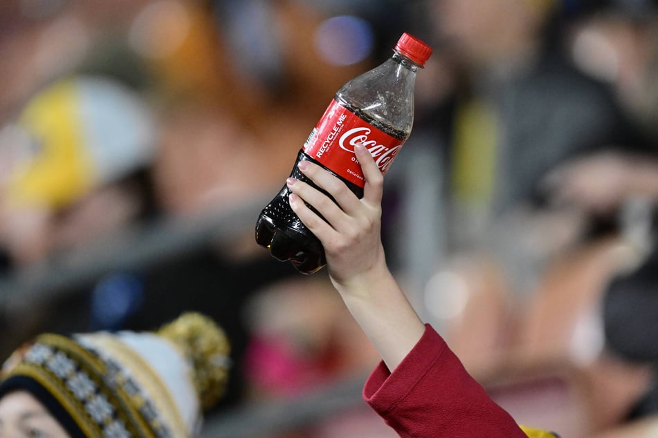 Fans hold up Coca-Cola bottles during a soccer match at America First Field in Sandy, Utah.