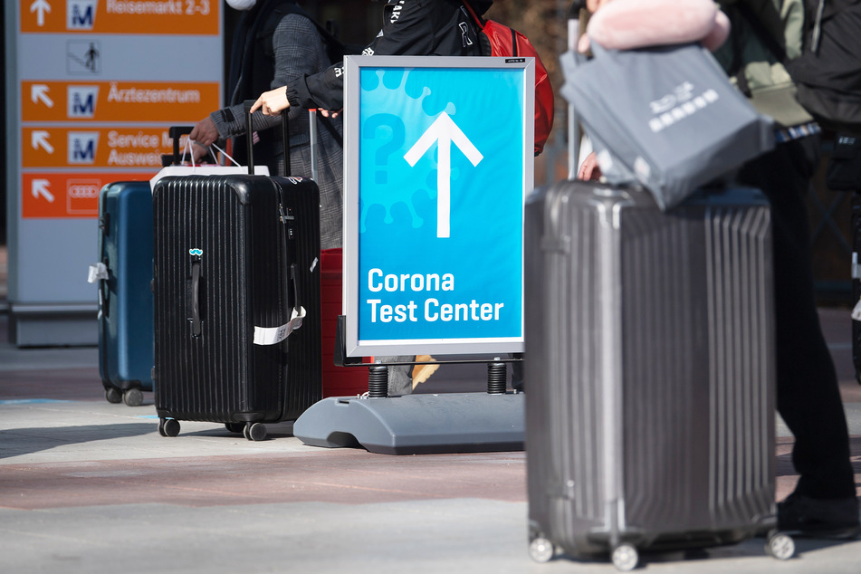 Reisende gehen an einem Flughafen zum Corona-Testzentrum.