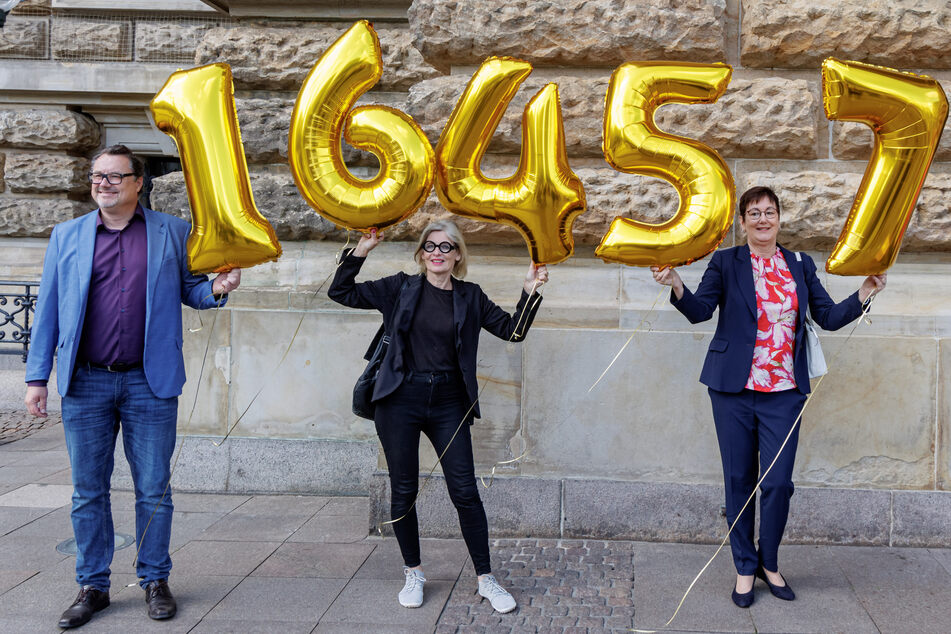 Mitglieder der Volksinitiative halten vor dem Rathaus Ballons mit der Zahl 16.457 in die Höhe.