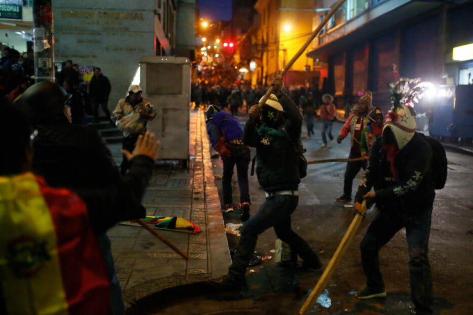 Mit einem Stock versucht ein Anhänger von Präsident Morales auf einen Demonstranten einzuschlagen.