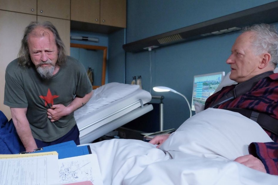 In der Sachsenklinik bezieht er ausgerechnet mit seinem ungeliebten Bruder Thomas (r.) ein Zimmer. Dort facht der Streit wieder auf. Doch plötzlich bricht Wolfgang zusammen. Wie reagiert sein Bruder?