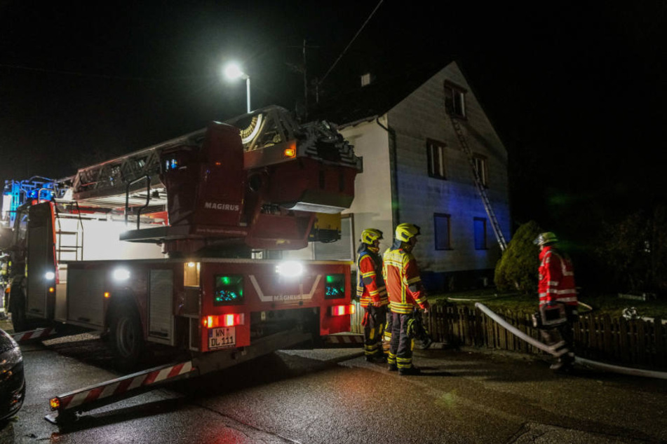 Die Feuerwehr mit dem Löschzug vor dem Haus. Am Fenster lehnt eine Leiter.