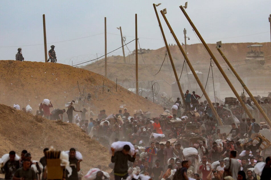 Palestinians carry aid supplies which they received from the US-backed Gaza Humanitarian Foundation in the central Gaza Strip on August 1, 2025.