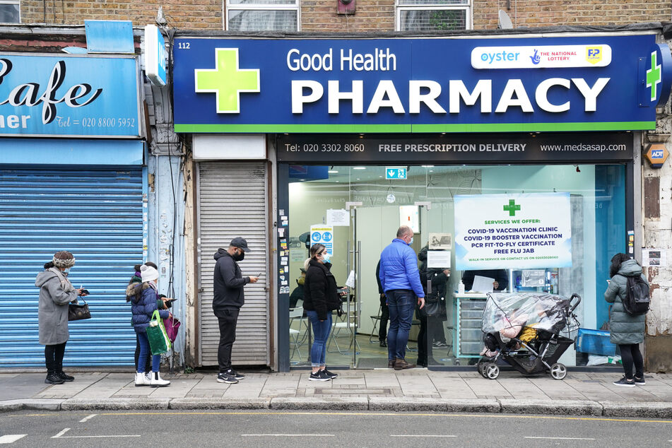 Menschen stehen vor der Good Health Pharmacy im Norden Londons, um eine Corona-Auffrischungsimpfung zu erhalten. Ihr Impfnachweis ist wohl ab nächster Woche nicht mehr nötig.