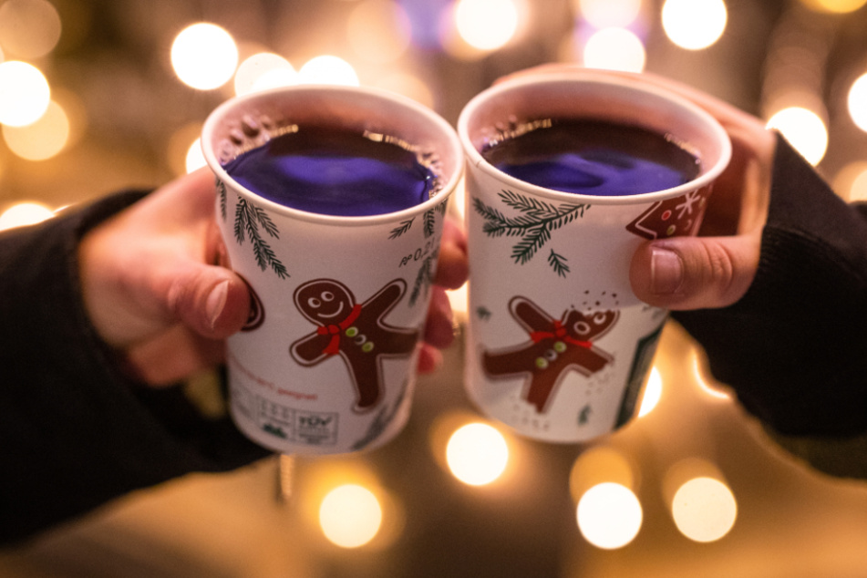 Zwei Frauen stoßen auf dem Schlossplatz in Stuttgart mit Glühwein an.