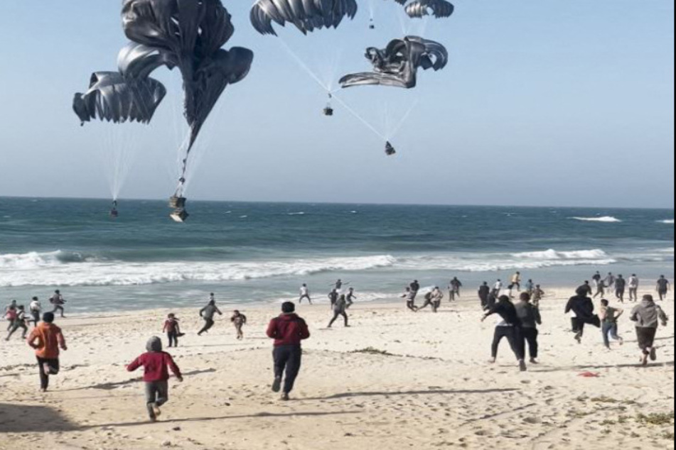 An einem Strand im Gaza-Streifen kommen Menschen zusammen, um von der US-Armee abgeworfenen Hilfsgüter im Empfang zu nehmen.